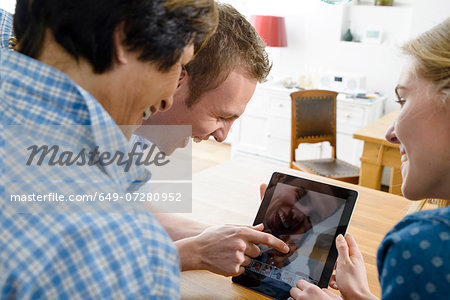 Grandmother and adult grandchildren using distortion on digital tablet Grandmother and adult grandchildren using distortion on digital tablet
