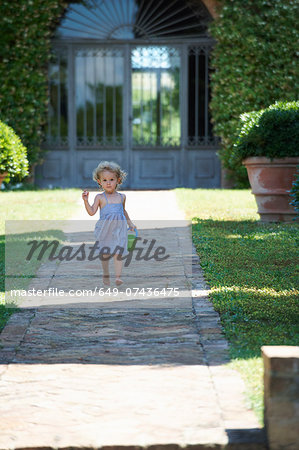 Girl running through garden carrying bucket