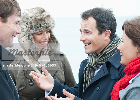 Two adult couples talking on beach, Thurlestone, Devon, UK