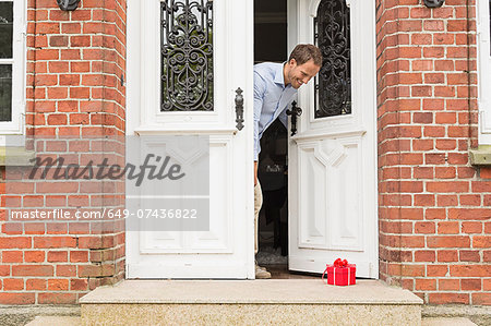 https://image1.masterfile.com/getImage/649-07436822em-mid-adult-man-with-gift-on-front-doorstep-stock-photo.jpg