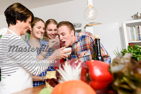 Mother, daughters and son tasting food