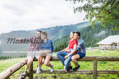 Four friends sitting on fence, Tyrol Austria