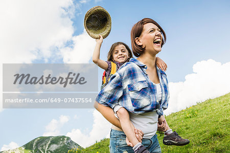 Mother and daughter on hike, girl holding straw hat