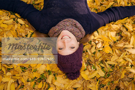 Young woman lying in autumn leaves