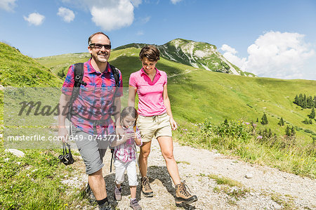 Parents and daughter walking on mountain track, Tyrol, Austria