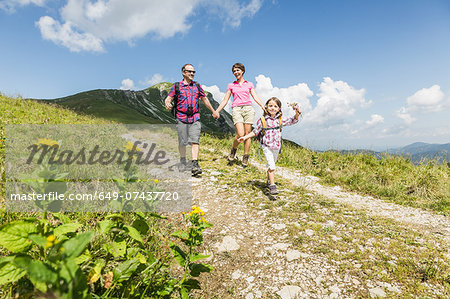 Parents and daughter walking on dirt track, Tyrol, Austria