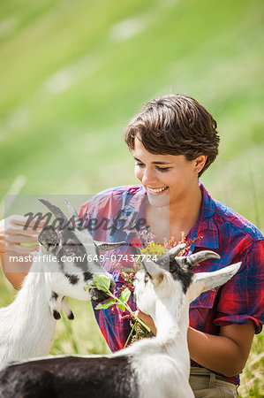 Young woman feeding kid goats, Tyrol, Austria