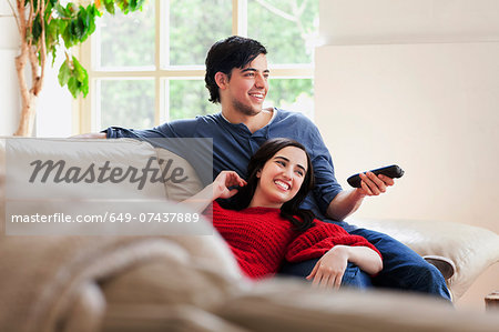 Young couple watching TV on living room sofa