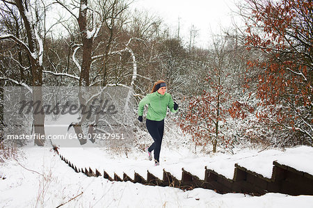 Female runner moving up snow covered staircase in winter