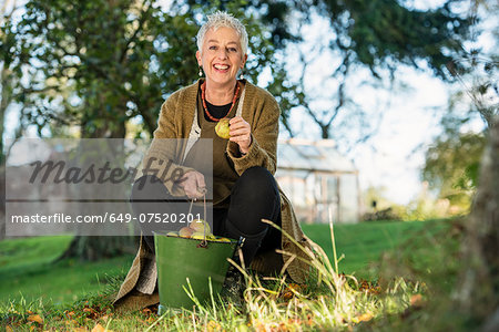 Senior woman holding apple from bucket