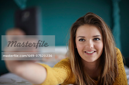 Teenage girl in bedroom taking a selfie