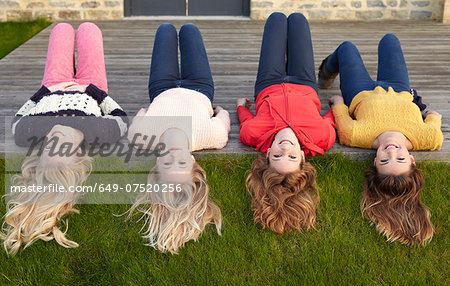 Four teenage girls lying on patio and looking back