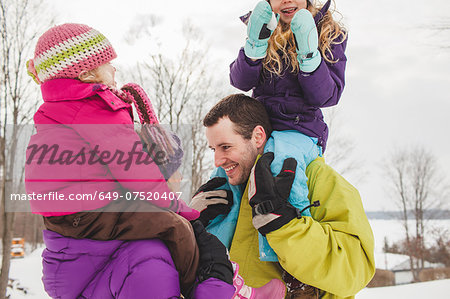 Mother and father carrying daughters in snow