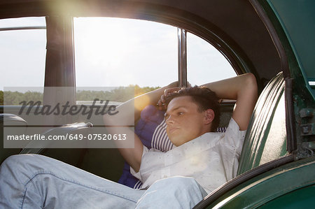 Young man posing in back seat of vintage morris minor