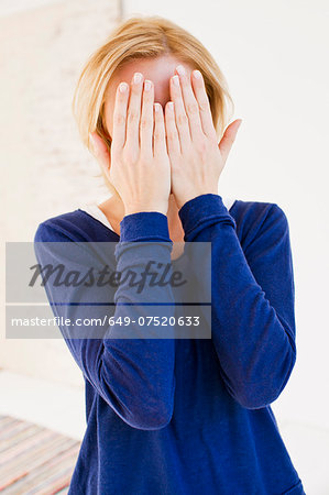 Studio portrait of young woman hiding behind hands