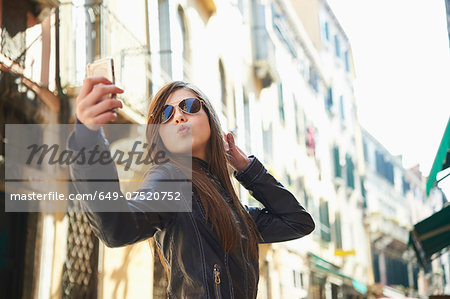 Girl taking selfie on smartphone, Venice, Italy