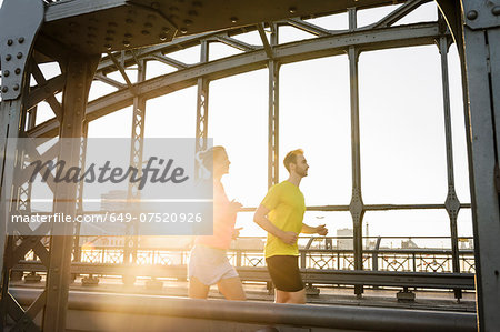 Young male and female running across bridge