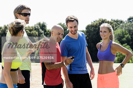 Mature male trainer and a group of adult runners looking at stopwatch