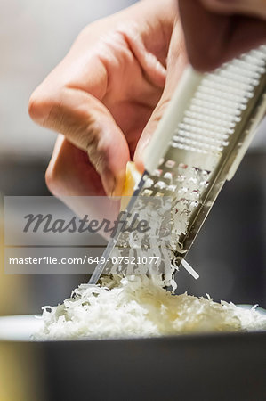 Close up of male hand grating parmesan cheese