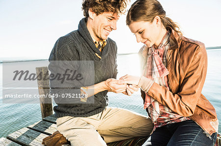 Man putting engagement ring on woman