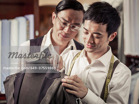 Father monitoring son in family tailoring business