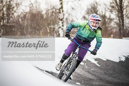 Young female mountain biker riding in snow