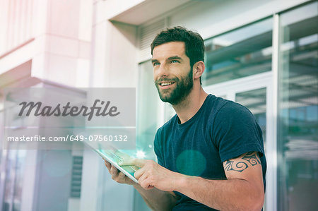 Mid adult man using touchscreen on digital tablet with lights Mid adult man using touchscreen on digital tablet with lights