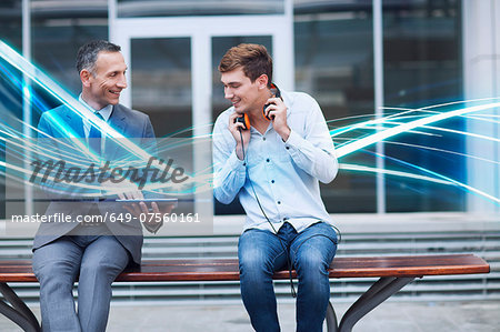 Businessman and young man watching digital tablet and waves of blue light