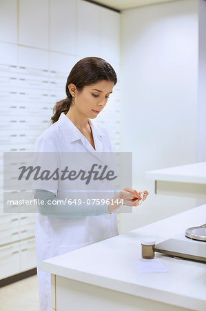 Young female pharmacist weighing medicines in pharmacy