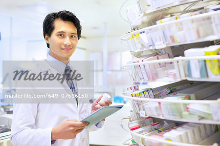 Portrait of male pharmacist stock taking in pharmacy