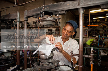 Hat maker measuring and chalking fabric in workshop