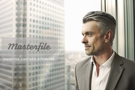 Portrait of mature businessman looking out of office window Portrait of mature businessman looking out of office window