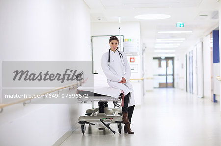 Portrait of female doctor sitting on hospital trolley in corridor