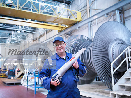 Portrait of engineer holding rotor blade in turbine repair workshop