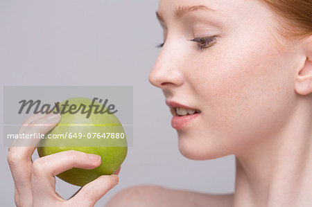 Portrait of young woman, holding green apple
