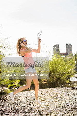 Young woman in park dancing whilst listening to headphones