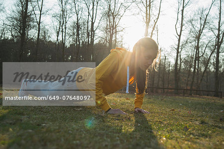 Young female runner doing warm up press ups
