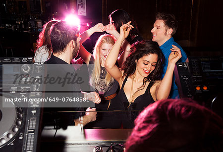 Group of friends dancing in front of  DJ in nightclub