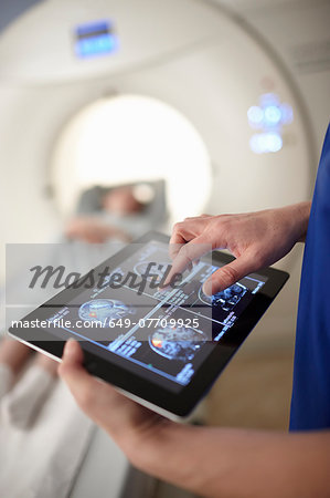 Radiographer looking at brain scan image on digital tablet