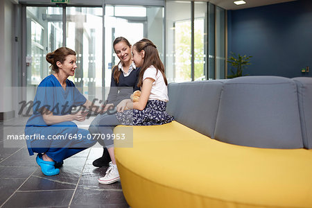 Nurse speaking to girl in hospital waiting room