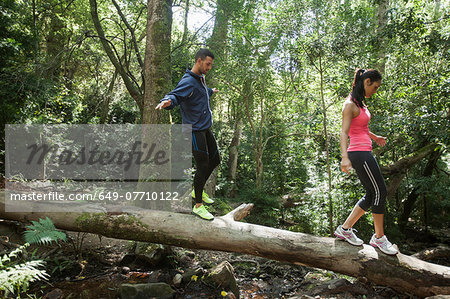 Young joggers balancing on tree trunk