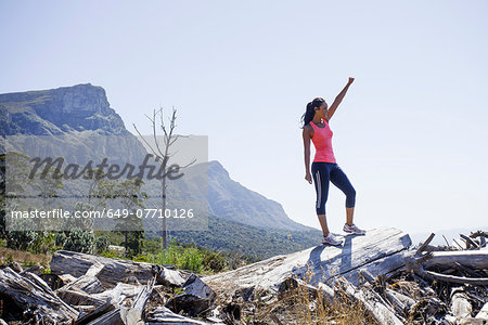 Female jogger in winning pose on hilltop