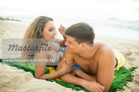 Young couple lying on brazilian flag, Ipanema Beach, Rio de Janeiro, Brazil