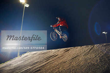 BMX-cyclist jumps his bike at night time