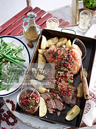 Still life of roast lamb with pomegranate seeds and vegetables