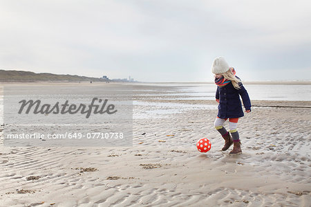 Three year old girl playing football on beach, Bloemendaal aan Zee, Netherlands