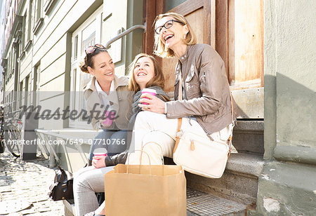 Three generation females drinking takeaway coffee on street