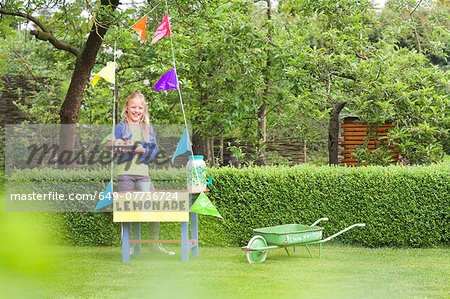 Lemonade stand girl with tray of apples behind her stand