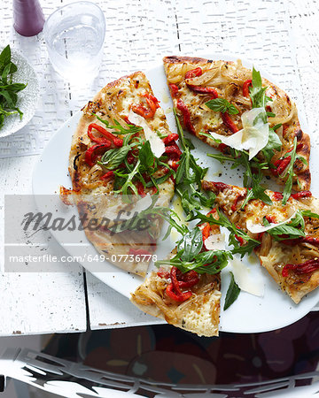 Plate of sliced wholemeal pizza with herbs, vegetable and parmesan