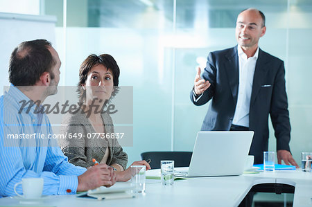 Businessmen and women arguing across boardroom table